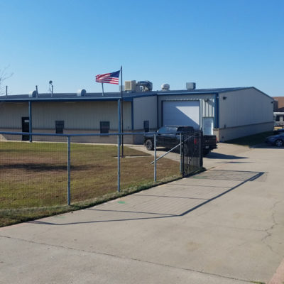 A fence is shown outside of an industrial building.