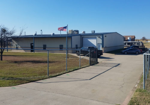 A fence is shown outside of an industrial building.